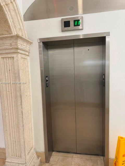 Elevator featuring a stainless steel door, brushed metal frame, and an arched stone-textured pilaster detail