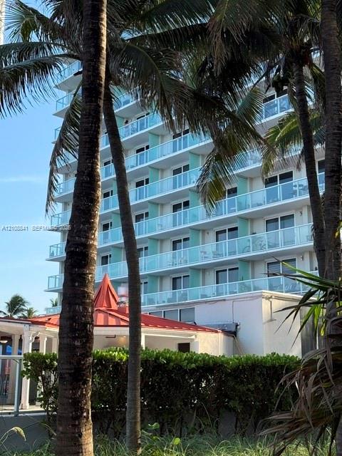 Multi-story exterior featuring tiered balconies with glass railings, large sliding glass doors, and a decorative red metal roof canopy