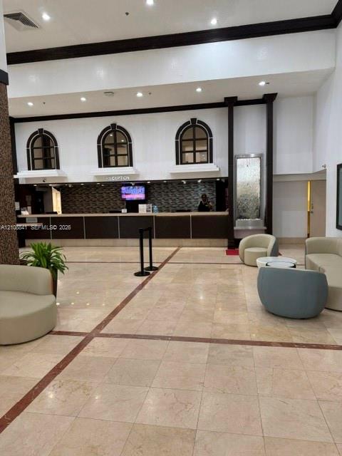 Lobby featuring stone tile flooring, an elongated service counter with a mosaic tile backsplash, built-in recessed arch windows, and an integrated wall-mounted water feature