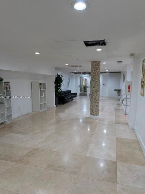 Open-concept interior featuring large-format tile flooring, recessed ceiling lighting, and a decorative textured support column
