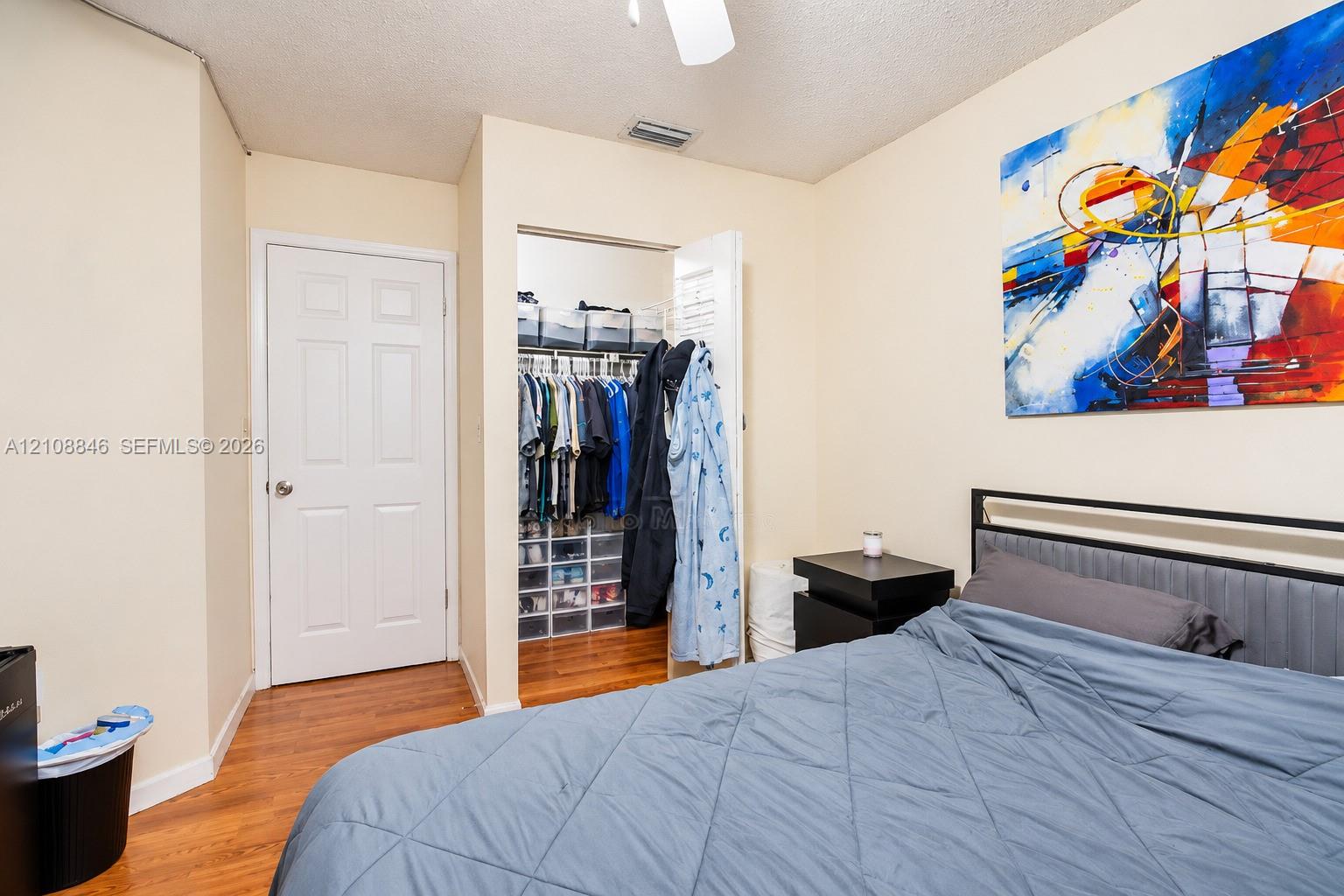 Room featuring wood-finish flooring and a walk-in closet with integrated wire shelving