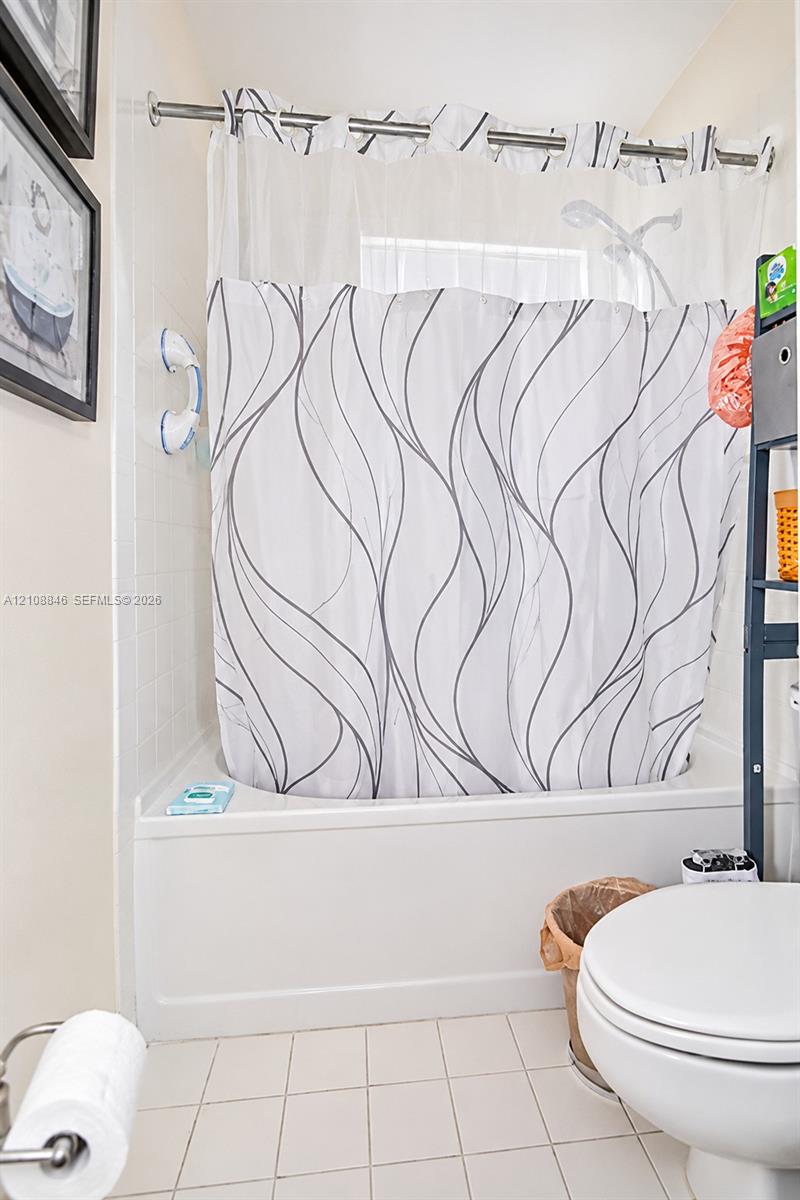 Tub-shower combination featuring white tile surround, integrated shelving, and metal shower rod hardware