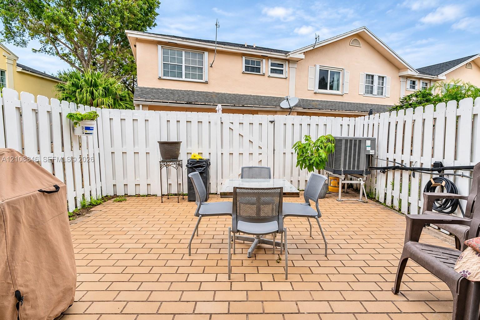 Private courtyard featuring light-toned paved flooring and a full-perimeter white vinyl fence