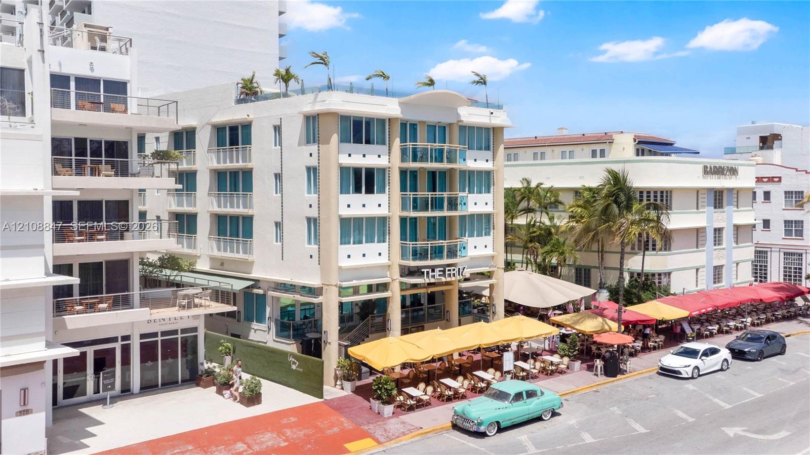 Multi-story building exterior featuring a reinforced concrete facade, integrated glass-railing balconies, floor-to-ceiling windows, and a rooftop terrace