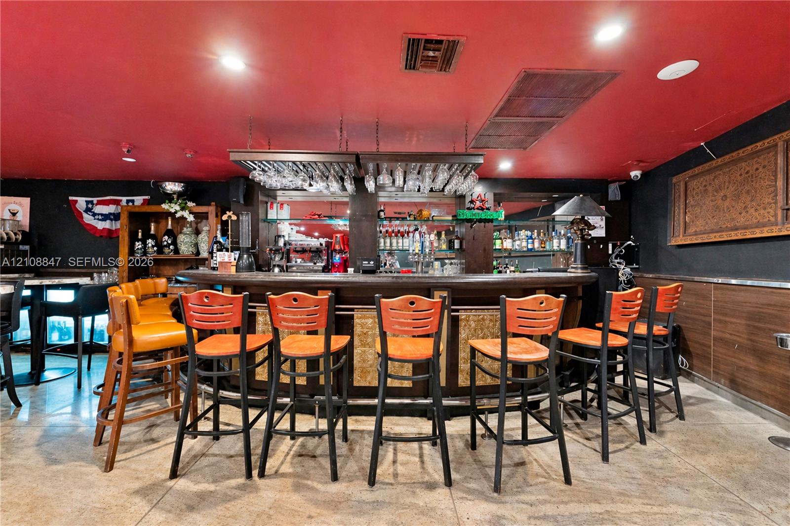 Curved bar area featuring a stone countertop, built-in glass stemware rack, recessed lighting, and stone flooring