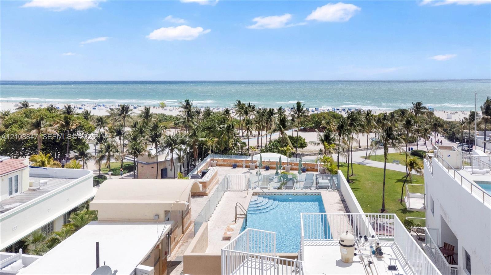 Rooftop swimming pool featuring glass panel perimeter fencing, masonry hardscaping, and an expansive ocean backdrop