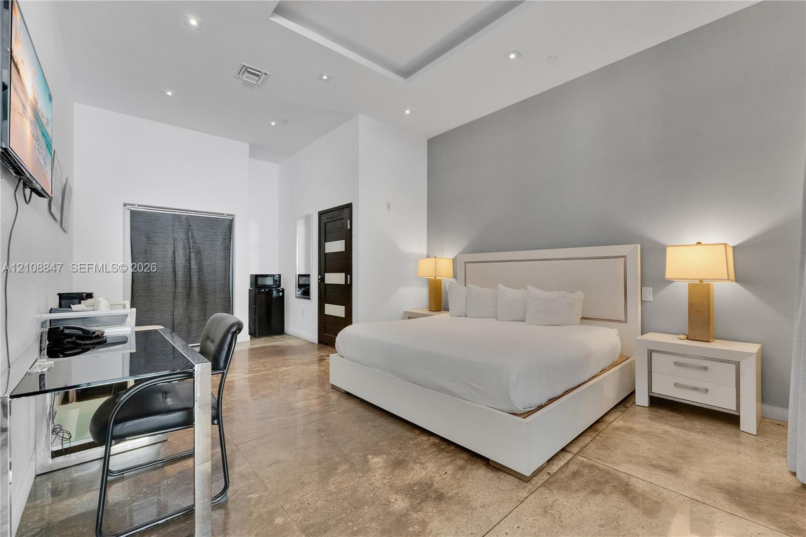 Tray ceiling with recessed lighting, polished stone flooring, and a decorative multi-panel interior door