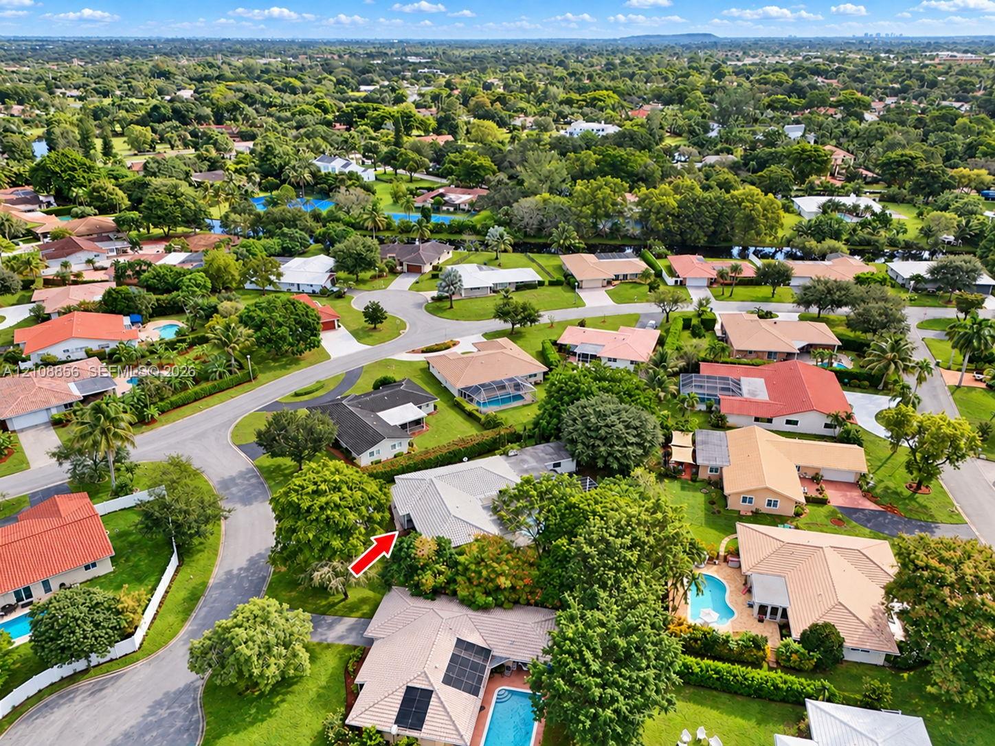 Aerial perspective of a suburban neighborhood featuring tree-lined streets, landscaped lots, and proximity to green space