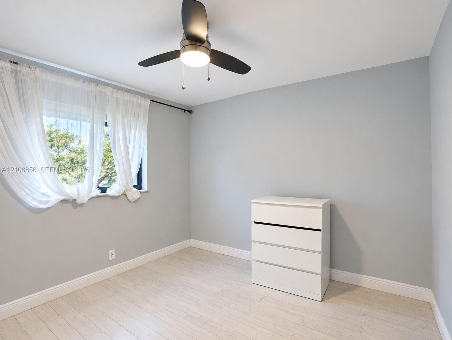 Neutral-toned walls, wood-finish flooring, and a modern ceiling fan with integrated lighting