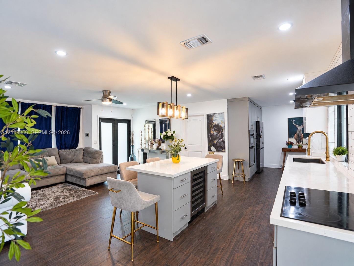 Kitchen featuring a central island with a built-in wine refrigerator, quartz countertops, wood-finish flooring, recessed lighting, and a modern industrial-style pendant light