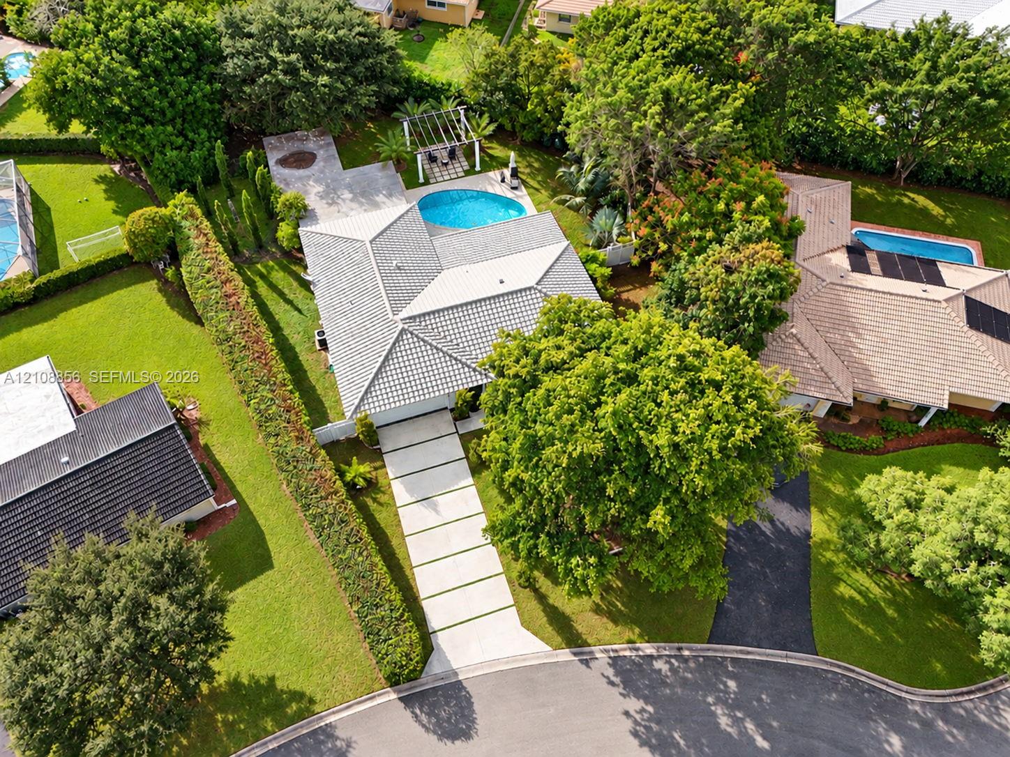Aerial perspective featuring a tile roof, concrete paver driveway with turf accents, swimming pool, and pergola