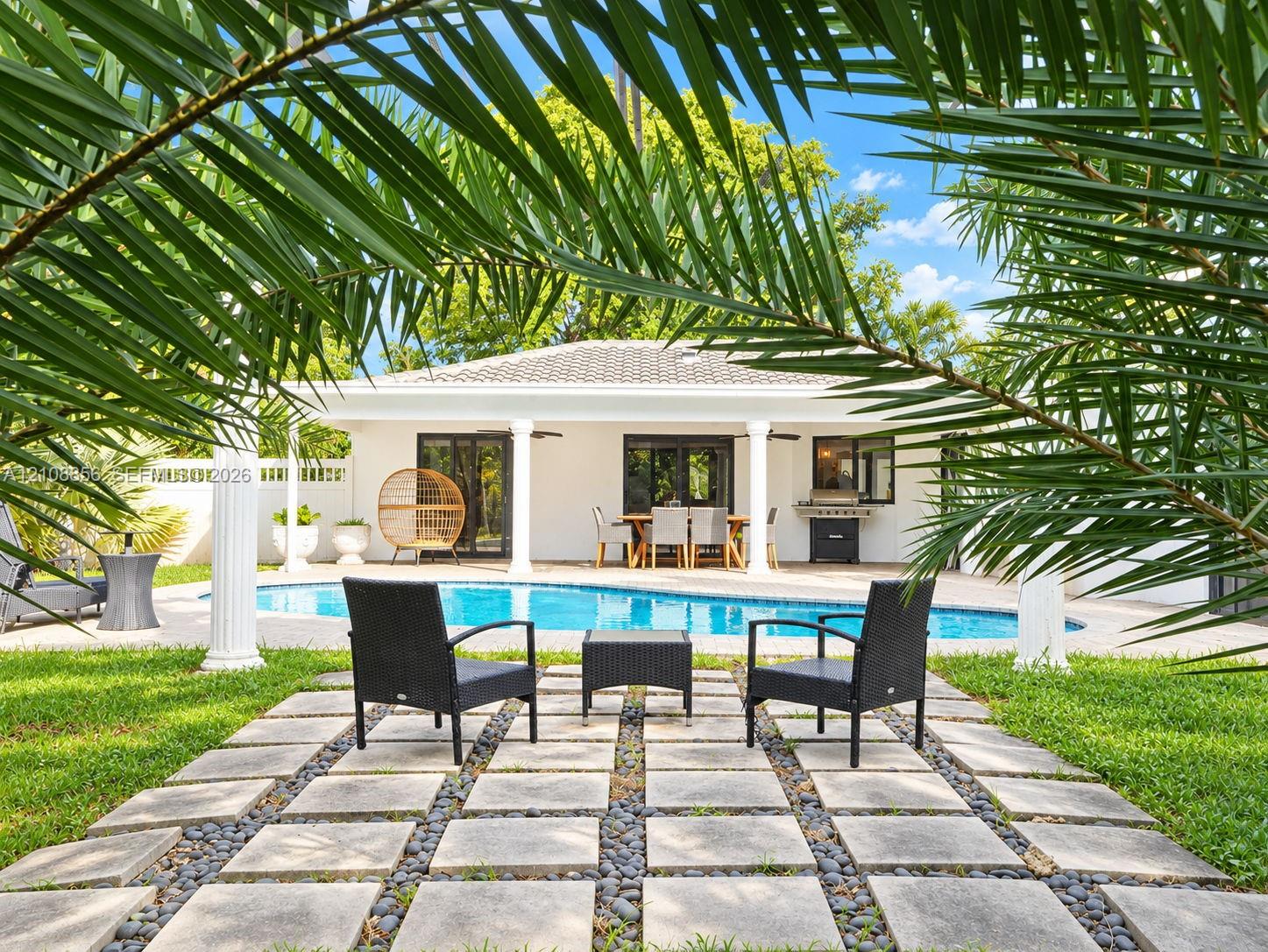 Outdoor space featuring a swimming pool, concrete paver grid patio with stone inlay, covered patio area, and architectural columns