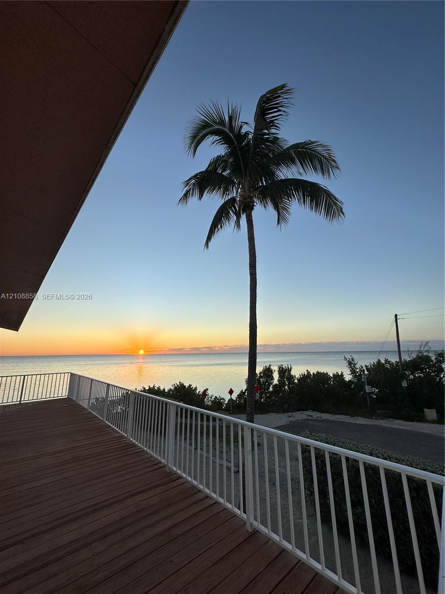 Elevated deck featuring wood-finish flooring, white metal railing, and ocean horizon Elevated deck featuring wood-finish flooring, white metal railing, and ocean horizon