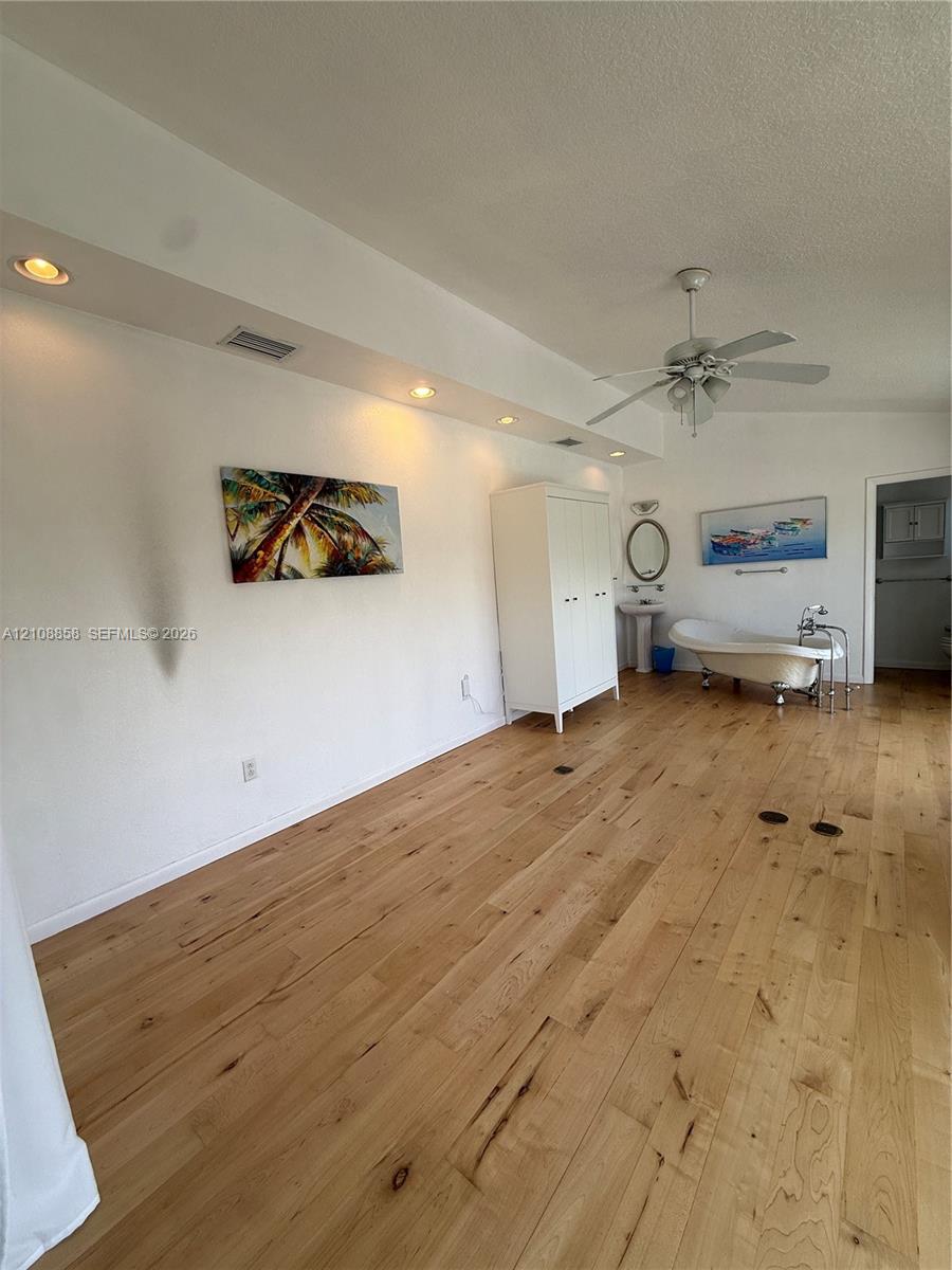 Wood-finish flooring, recessed ceiling lighting, clawfoot soaking tub, pedestal sink, and ceiling fan Wood-finish flooring, recessed ceiling lighting, clawfoot soaking tub, pedestal sink, and ceiling fan