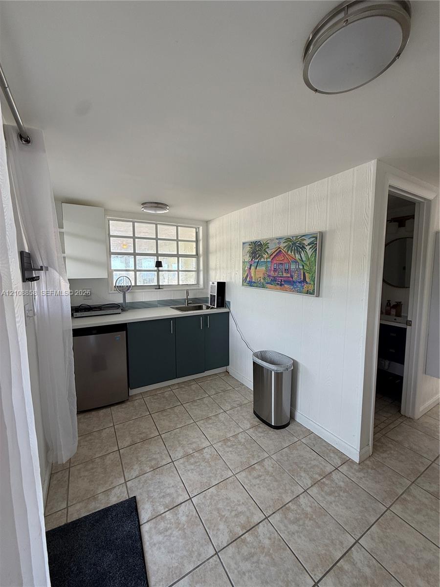 Kitchenette featuring flat-panel cabinetry, a light-toned countertop, integrated sink, and tile flooring