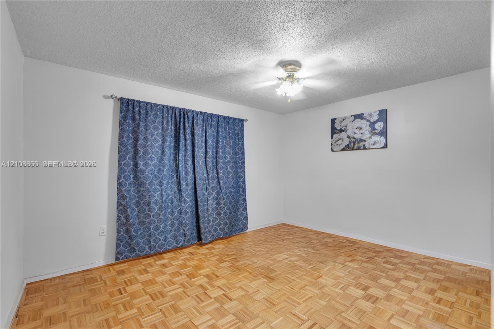 Parquet wood-finish flooring, textured ceiling, and a central ceiling fan with multi-light fixture
