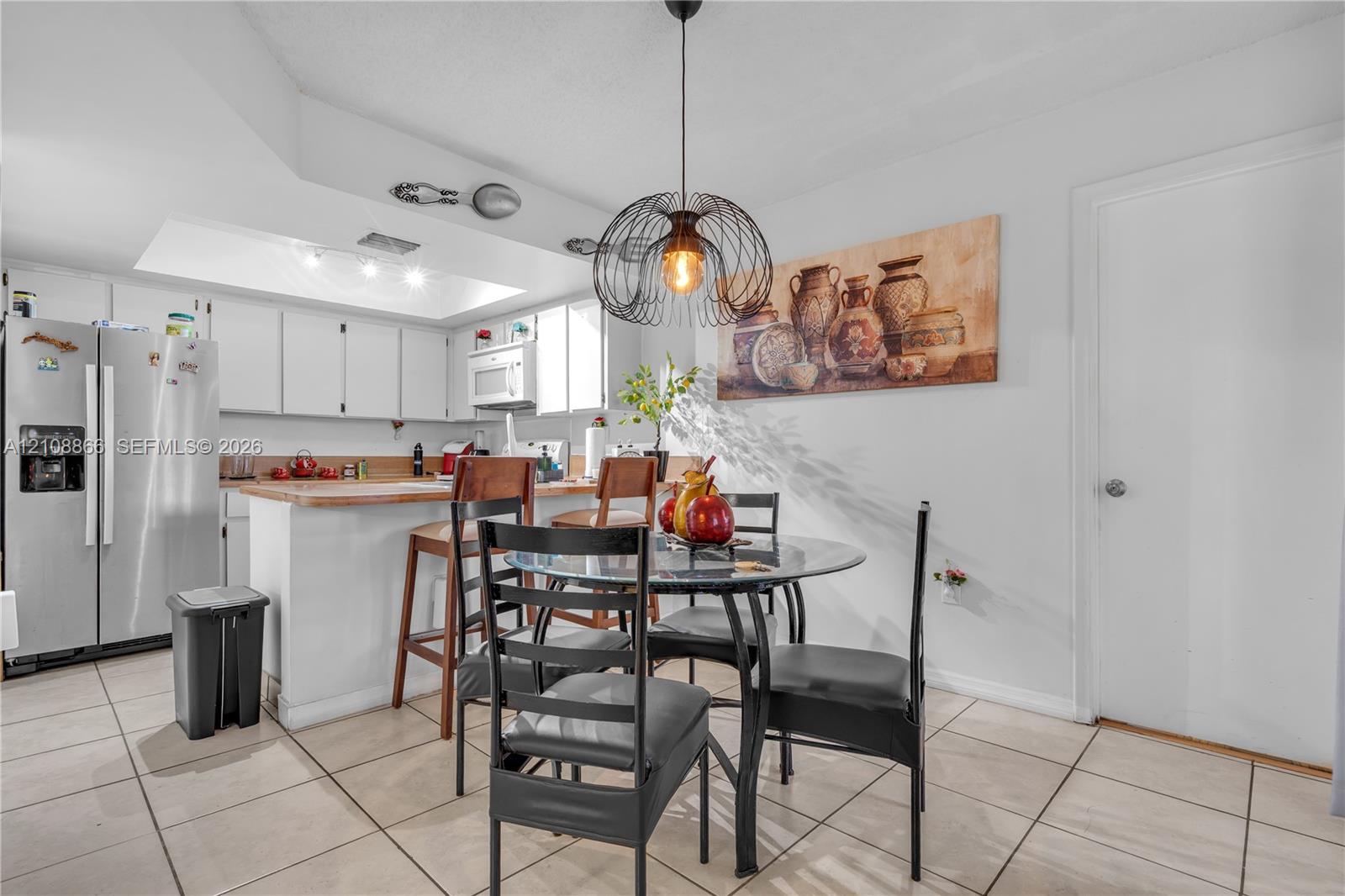 Kitchen featuring white cabinetry, wood-surface breakfast bar, recessed lighting, and tile flooring