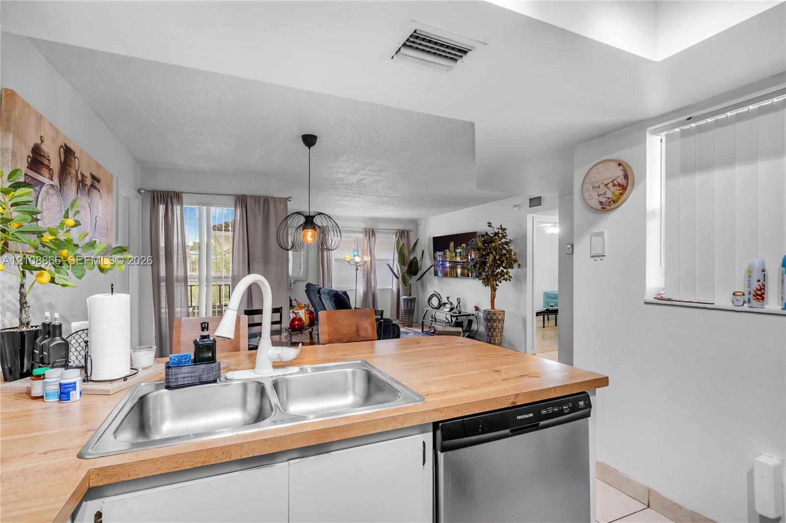 Kitchen featuring a wood-finish countertop, dual-basin stainless steel sink, gooseneck faucet, and stainless steel dishwasher