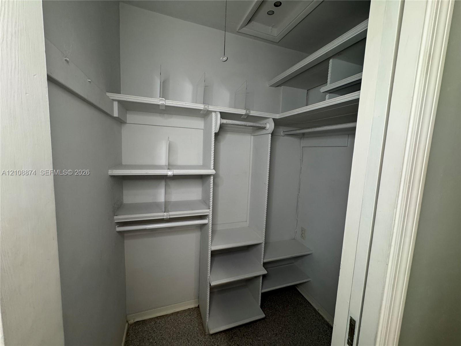 Storage closet featuring tiered built-in shelving, vertical dividers, and integrated garment rods