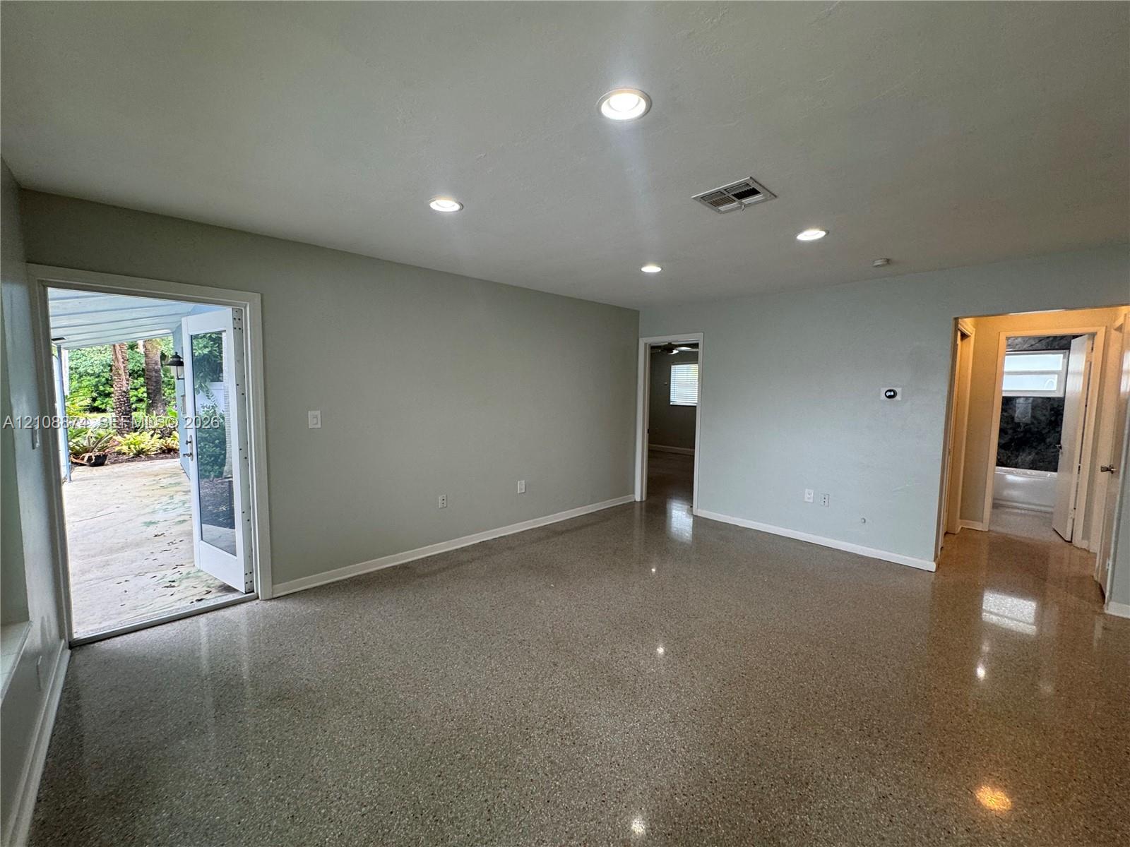 Polished terrazzo flooring, recessed lighting, and a glass-paneled door opening to an exterior concrete patio