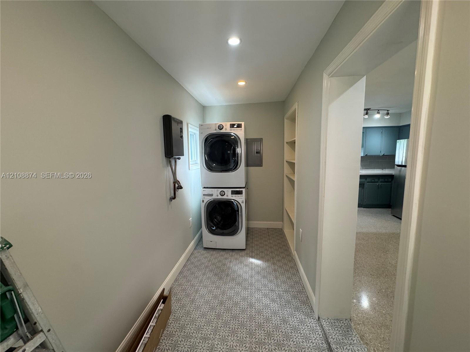 Utility space featuring patterned tile flooring, built-in recessed shelving, and recessed ceiling lighting