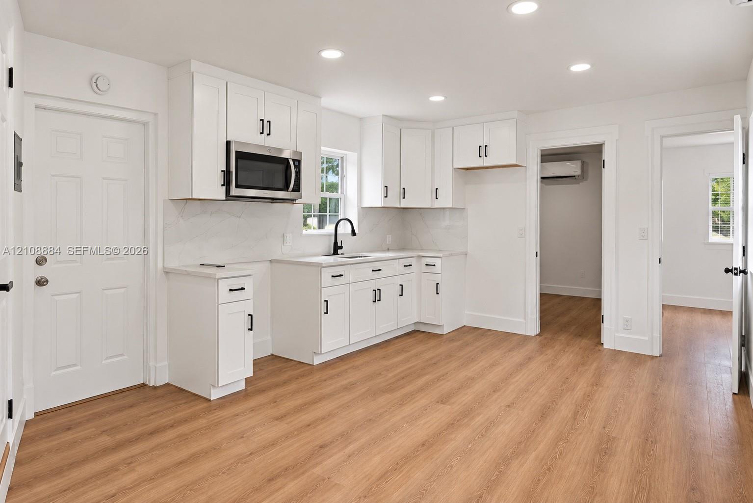 Kitchen featuring white shaker cabinetry, stone-finish countertops, recessed lighting, wood-finish flooring, and a stainless steel built-in microwave