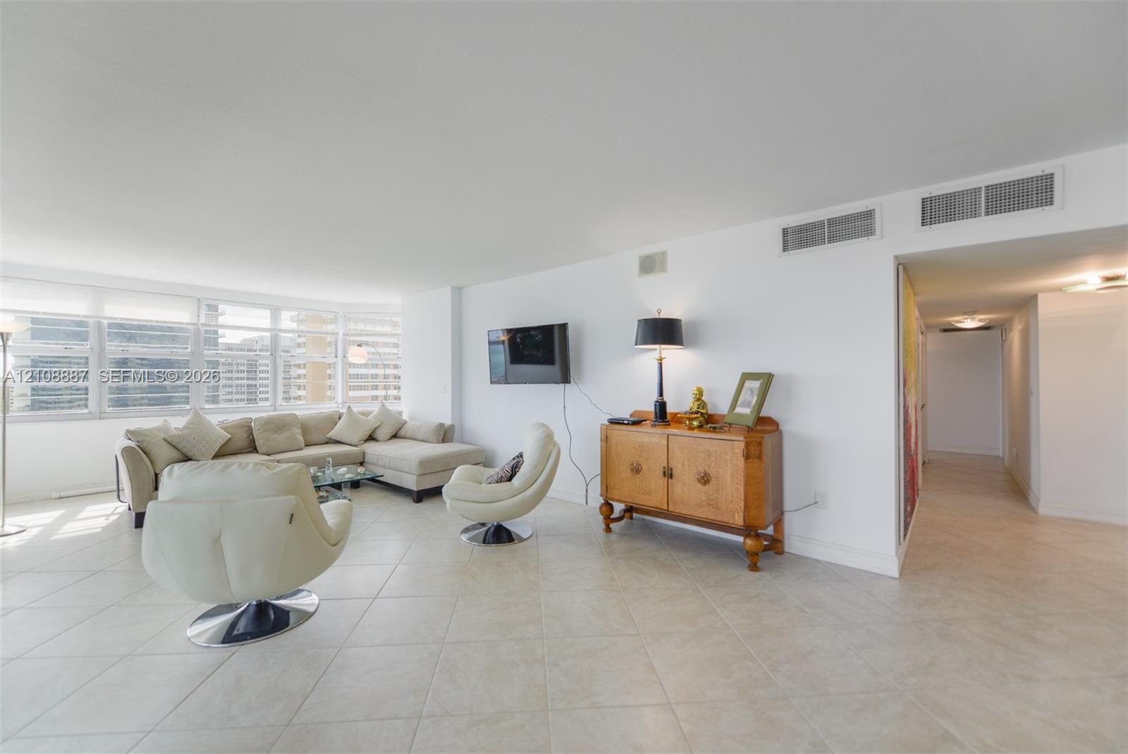 Open-concept interior featuring large-format ceramic tile flooring, expansive floor-to-ceiling windows, and neutral wall finishes