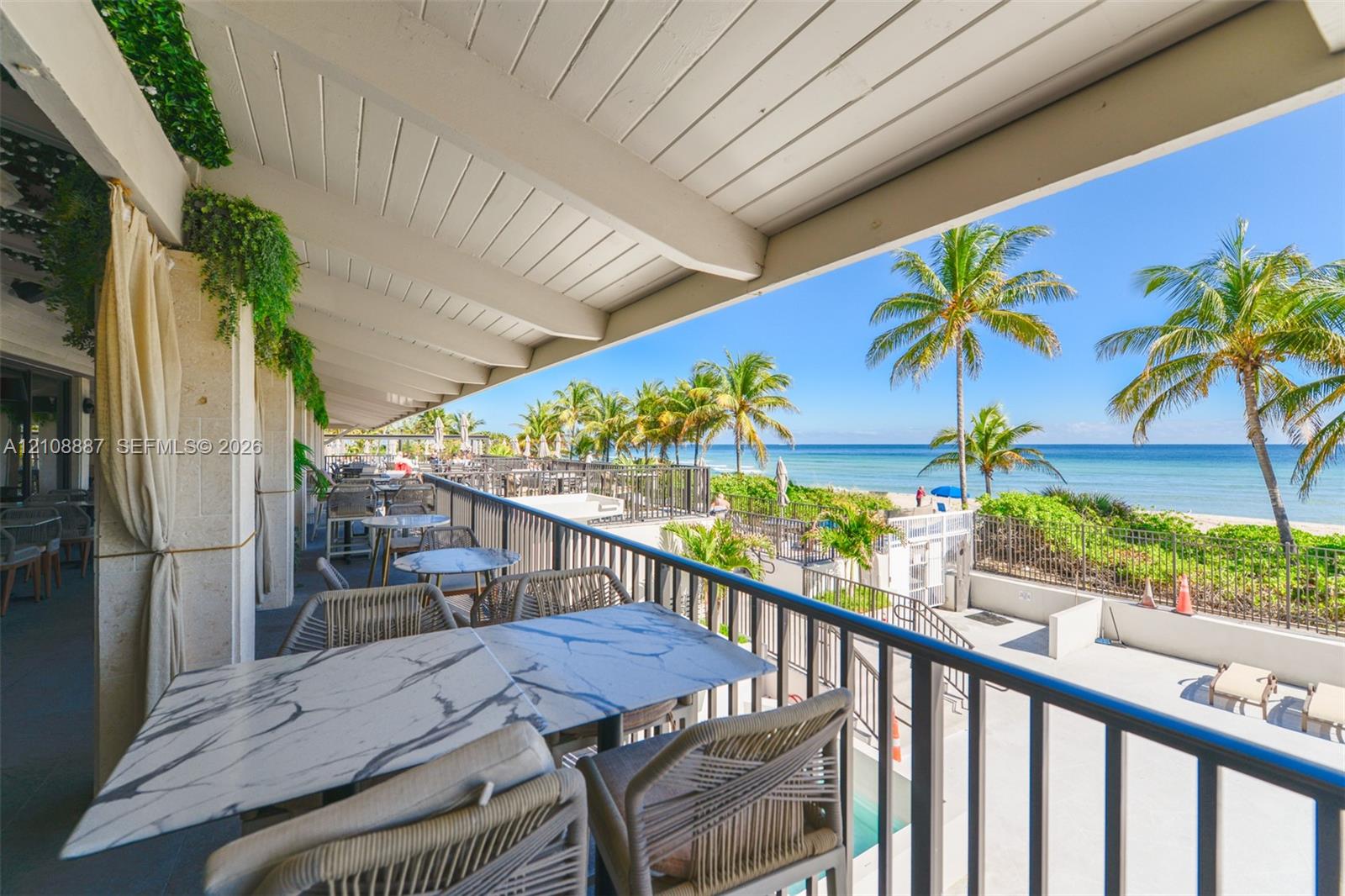 Covered outdoor patio featuring a slatted wood ceiling, metal railing, and direct water exposure