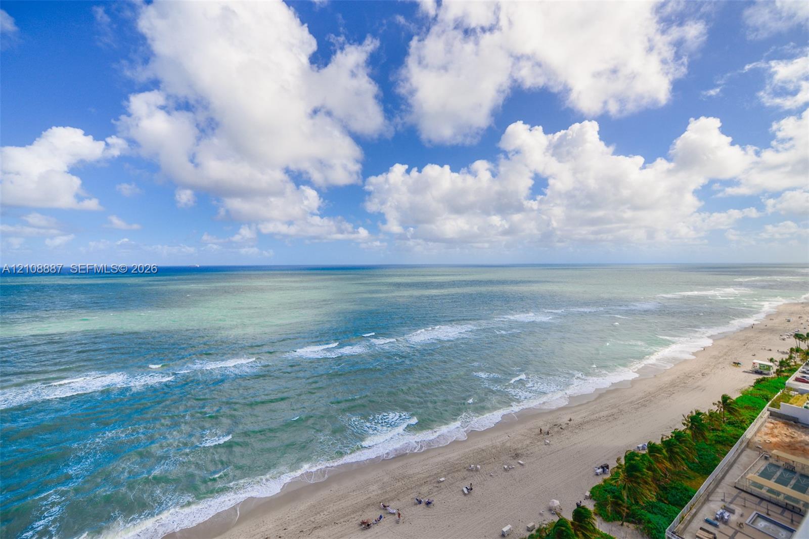 Elevated perspective of the coastline featuring expansive ocean frontage and direct access to the sandy beach