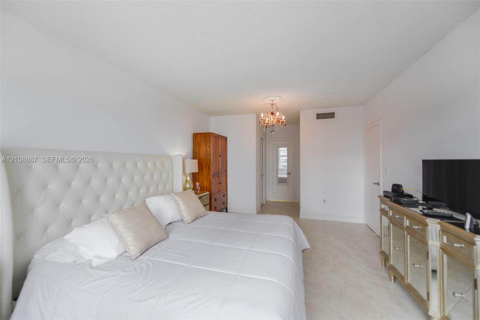 Neutral-toned tile flooring, recessed ceiling lighting fixture, and traditional white interior doors
