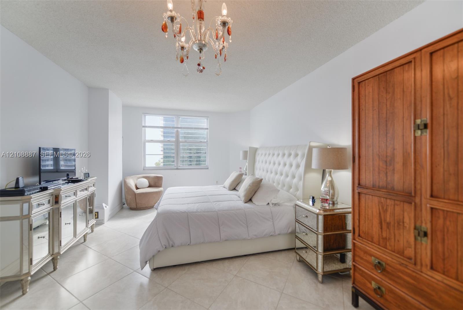 Room featuring large-format tile flooring, a multi-pane window, and an ornate, multi-arm crystal-style chandelier