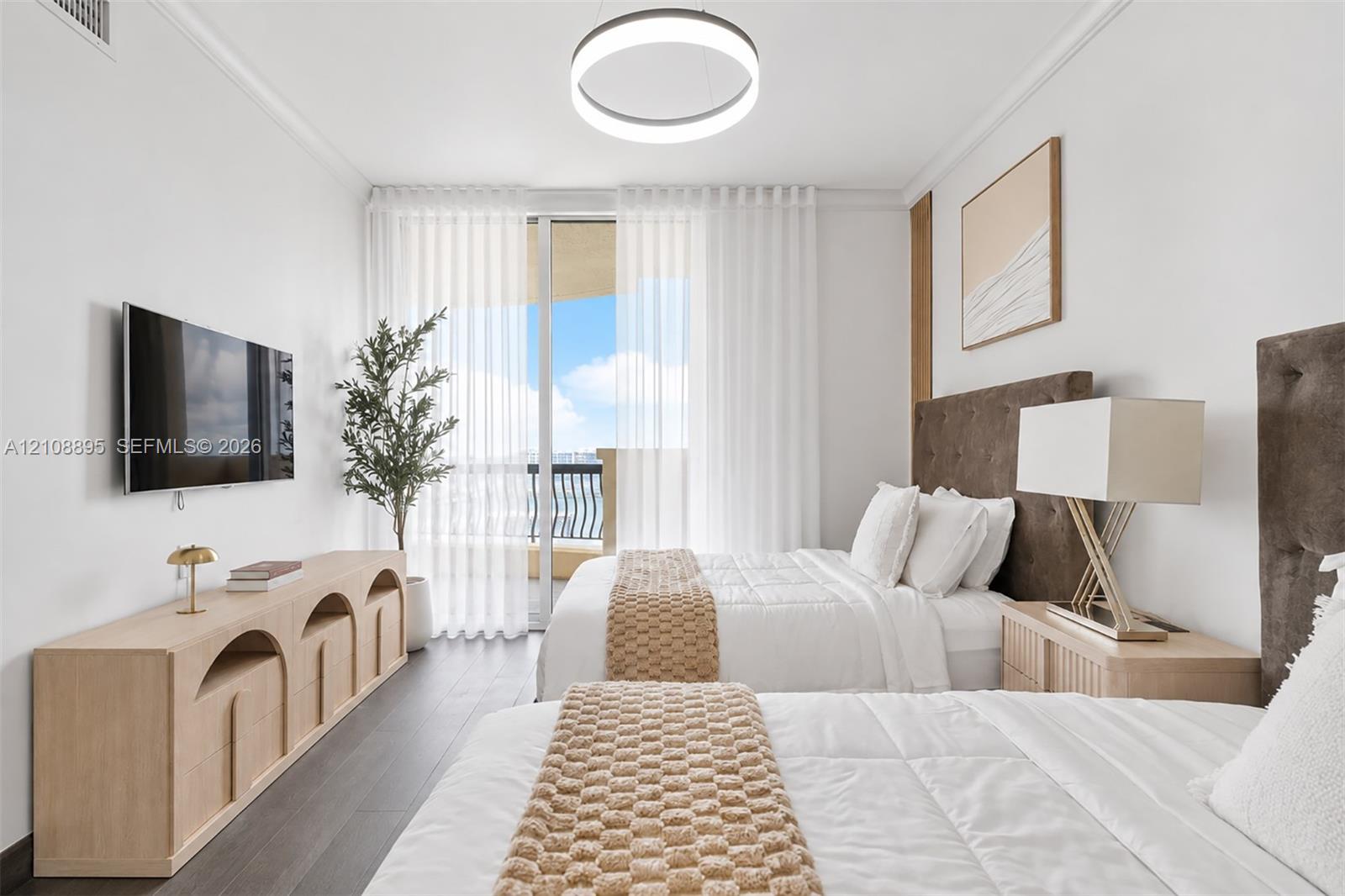 Floor-to-ceiling glass sliding doors opening to a balcony, dark wood-finish flooring, and a modern circular LED light fixture