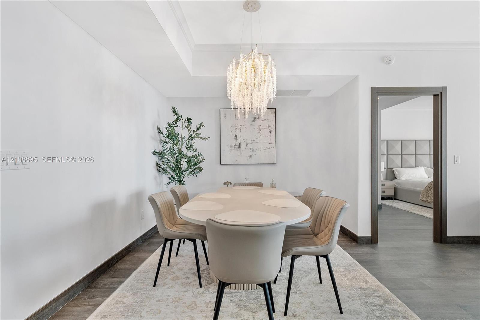 Dining area featuring charcoal tile flooring, recessed ceiling detail, and a tiered crystal chandelier