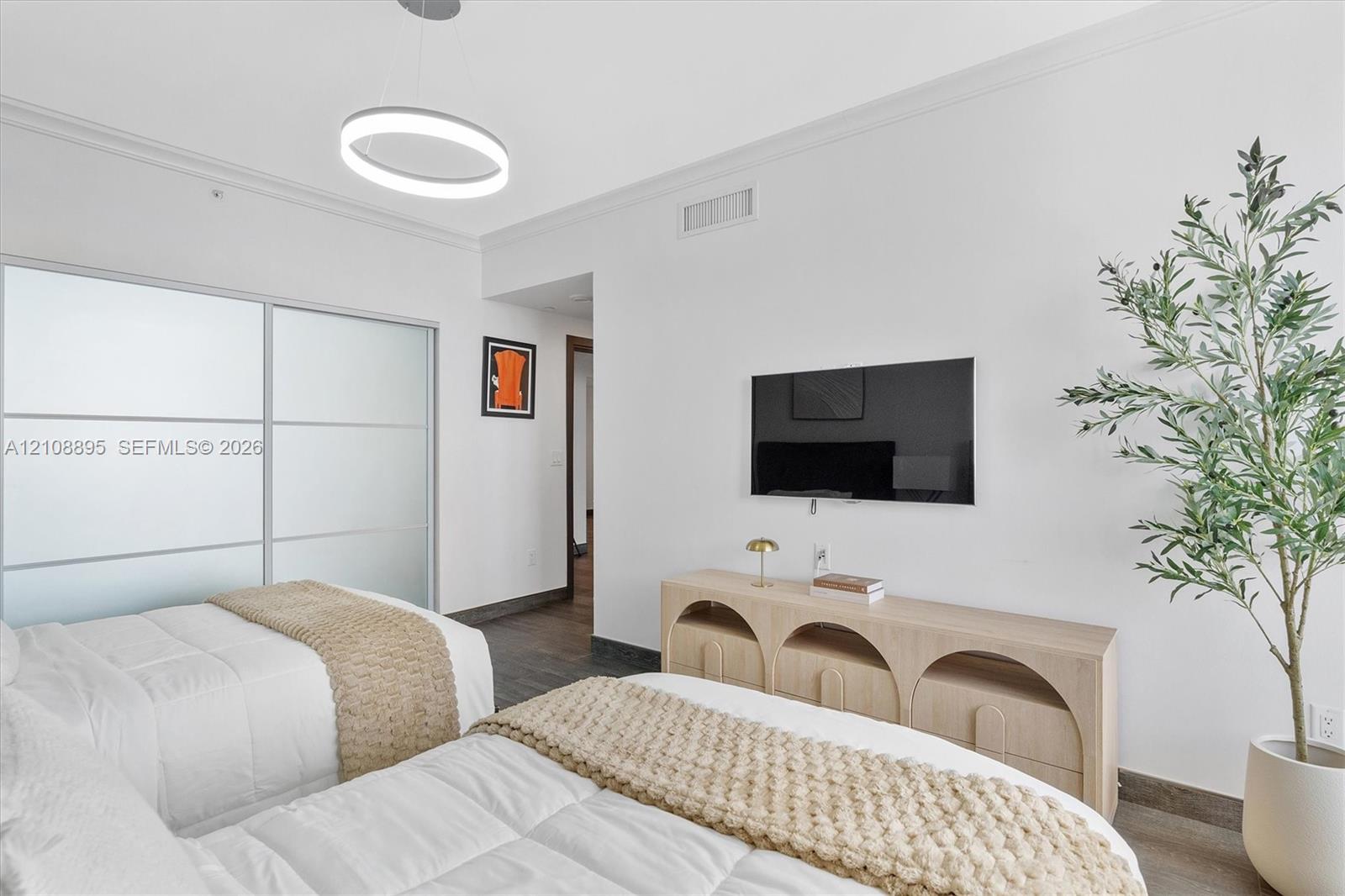Contemporary room featuring frosted-glass sliding closet doors, circular LED pendant lighting, wood-finish flooring, and crisp white walls