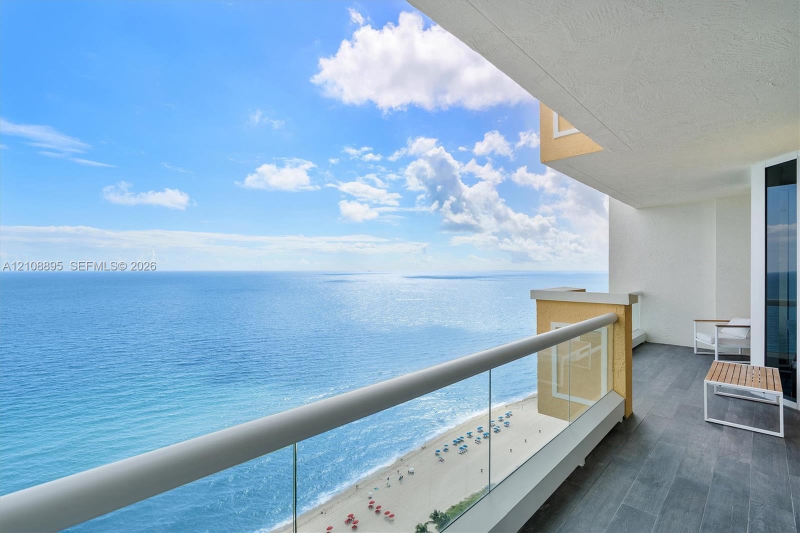 Covered balcony featuring dark-toned stone tile flooring and a glass panel railing