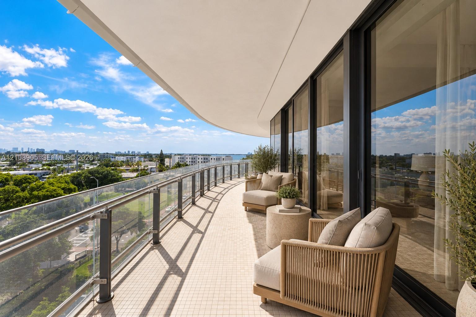 Curved balcony featuring tile flooring, glass panel railing with metal posts, and floor-to-ceiling glass wall