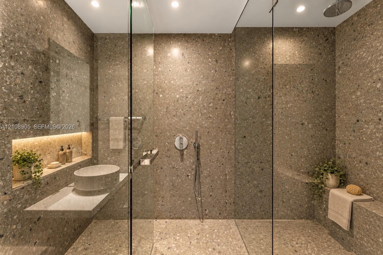 Full-height natural stone tiling, walk-in shower with frameless glass enclosure, wall-mounted faucet, floating vanity with vessel sink, and recessed integrated shelving with accent lighting