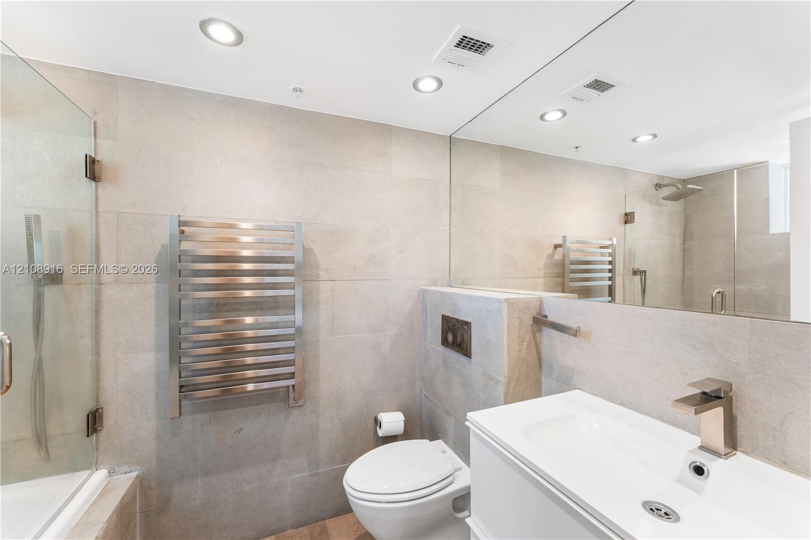 Beautifully remodeled master bathroom featuring a heated towel rack and a luxurious bathtub with a rainfall shower-head and convenient handheld shower for a spa-like experience.