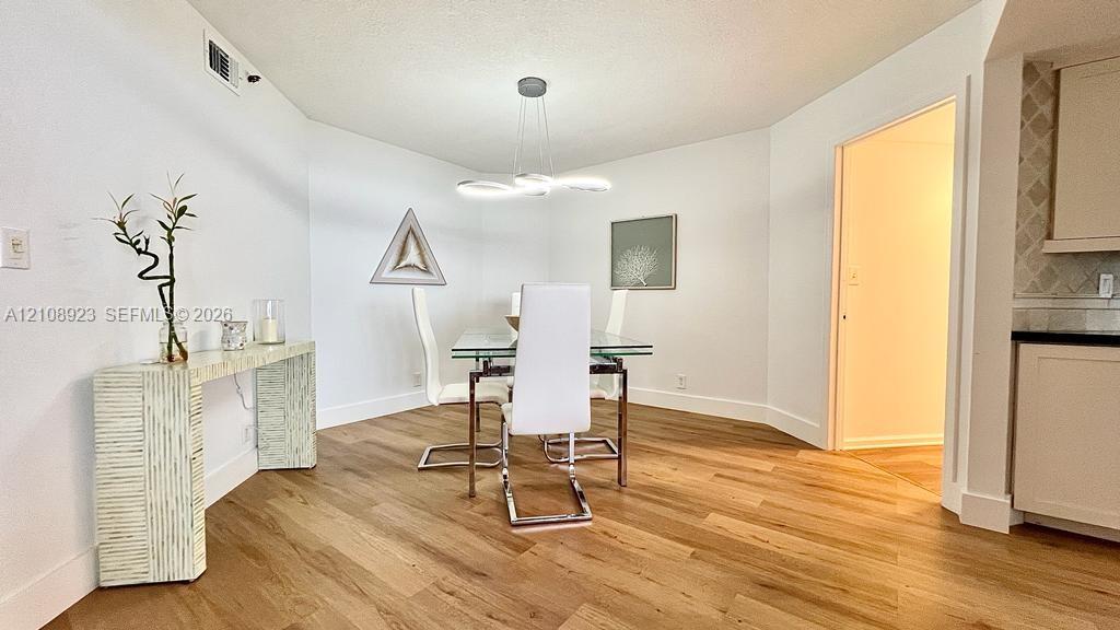 Dining area featuring wood-finish flooring, modern multi-ring LED chandelier, and recessed ceiling lighting