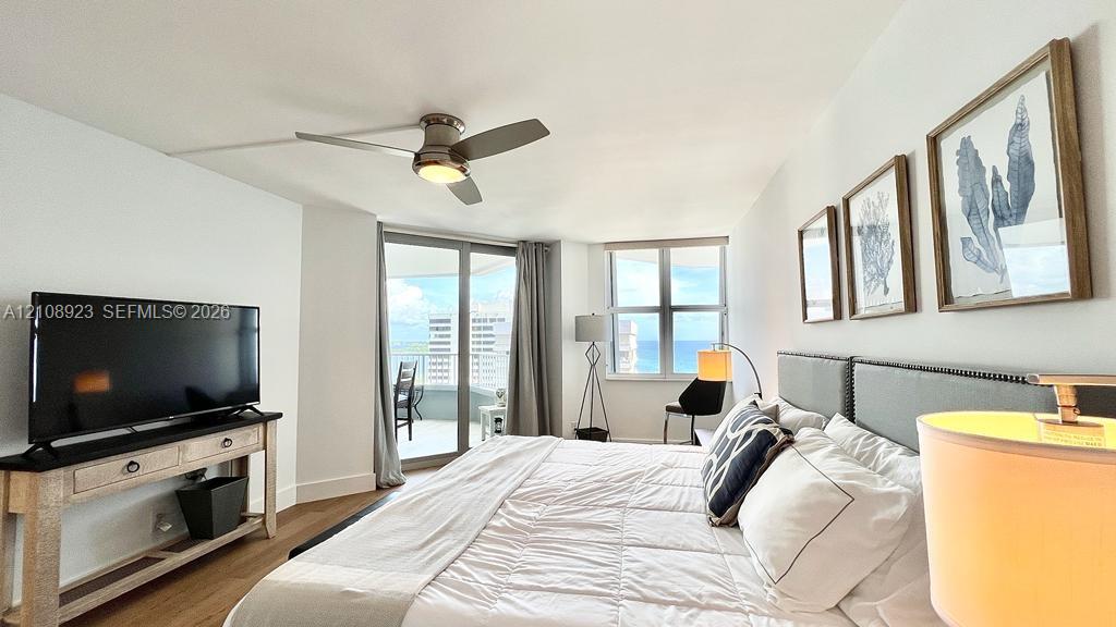 Wood-finish flooring, ceiling fan with integrated lighting, glass sliding doors, and large windows