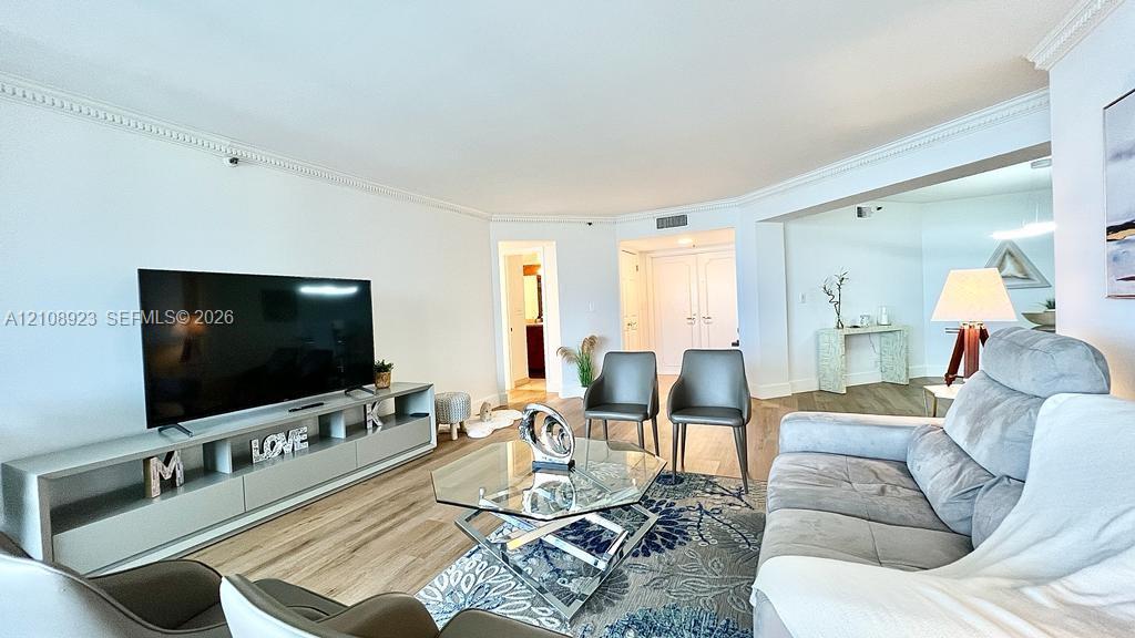 Living area featuring wood-finish flooring, crown molding, and built-in cabinetry