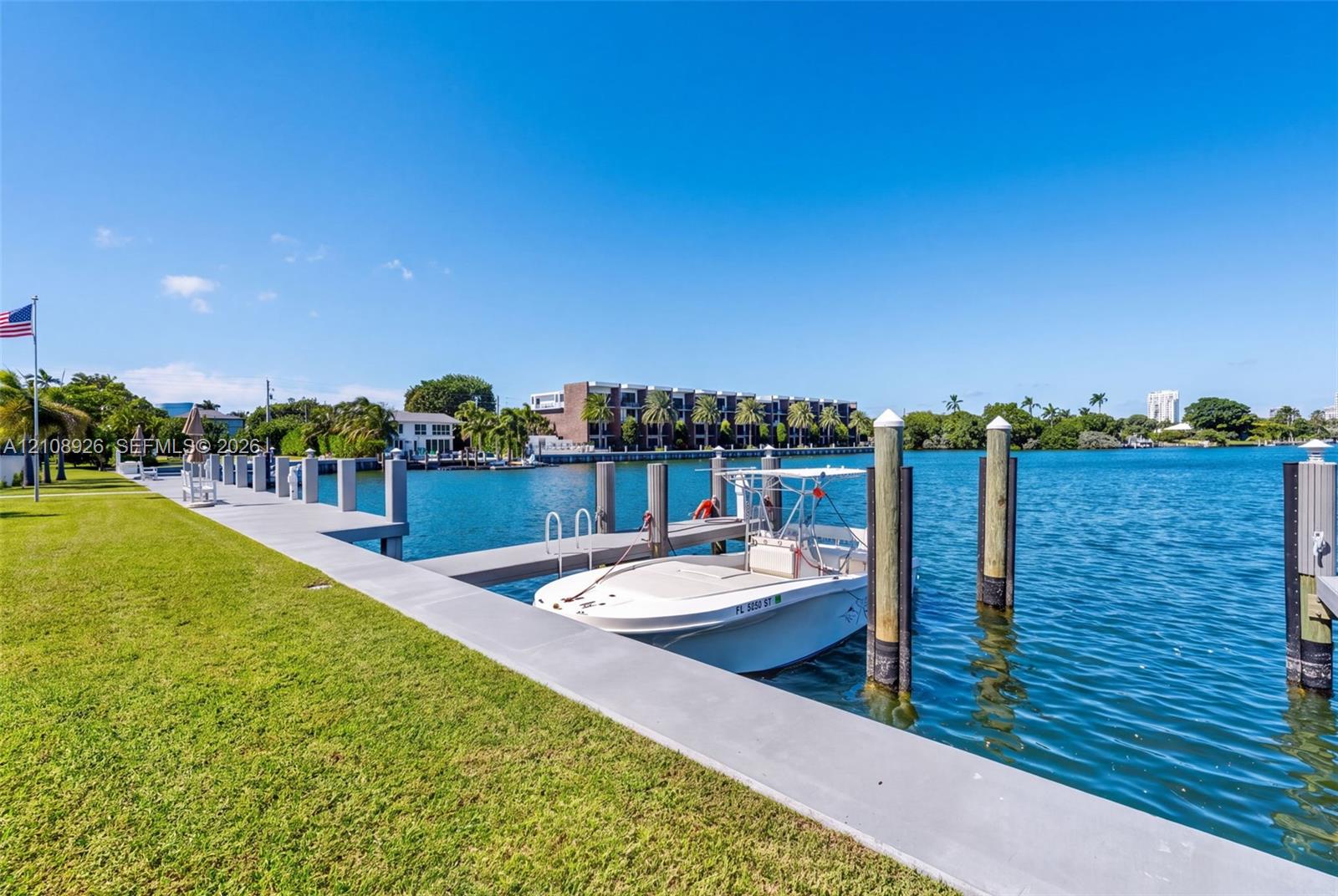 Waterfront property featuring a private concrete dock, nautical pilings, and a manicured lawn