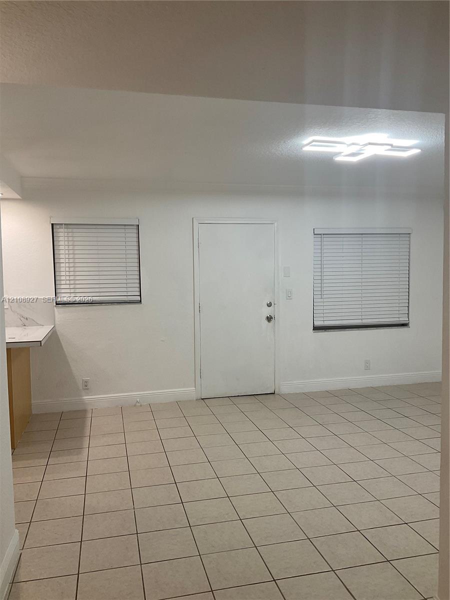 Neutral-toned ceramic tile flooring, modern geometric LED ceiling fixture, and dual windows with horizontal blinds