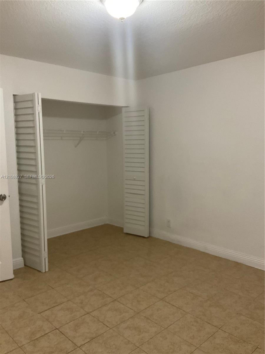 Room featuring tile flooring, a closet with white louvered bi-fold doors, and a ceiling-mounted light fixture