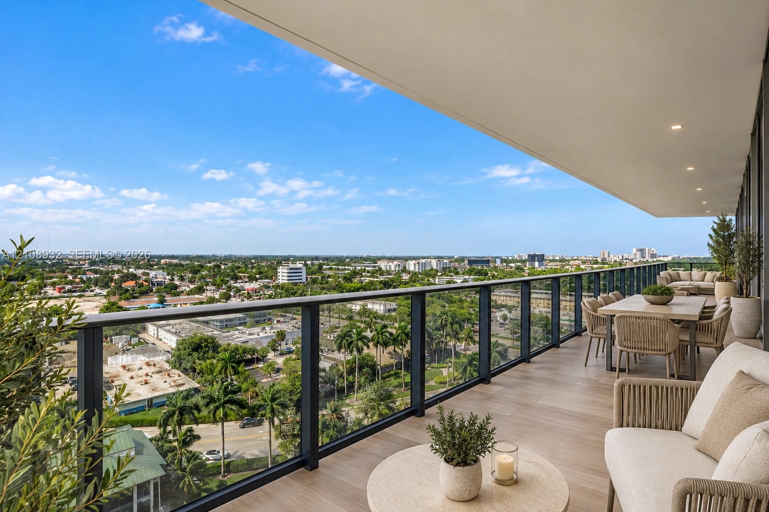 Expansive covered balcony featuring wood-finish flooring, recessed lighting, and a modern glass and metal railing system