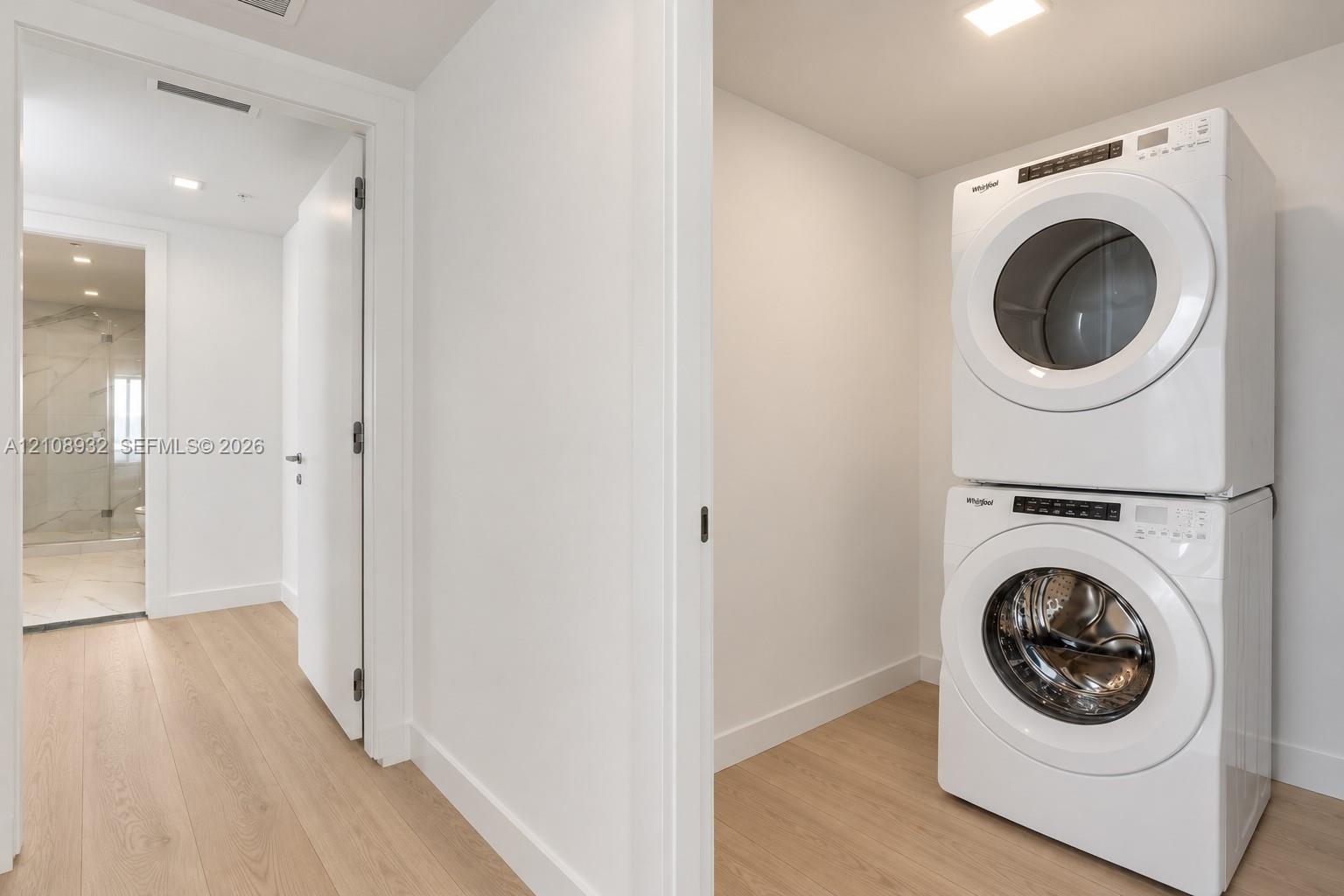 Stacked front-loading washer and dryer, wood-finish flooring, and recessed ceiling lighting