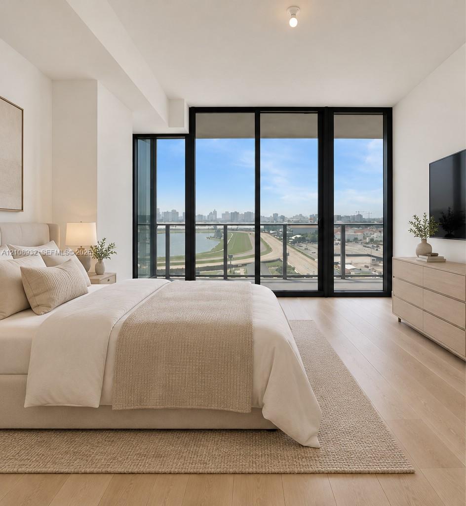 Floor-to-ceiling black-frame windows, wood-finish flooring, and a private balcony with an exterior railing