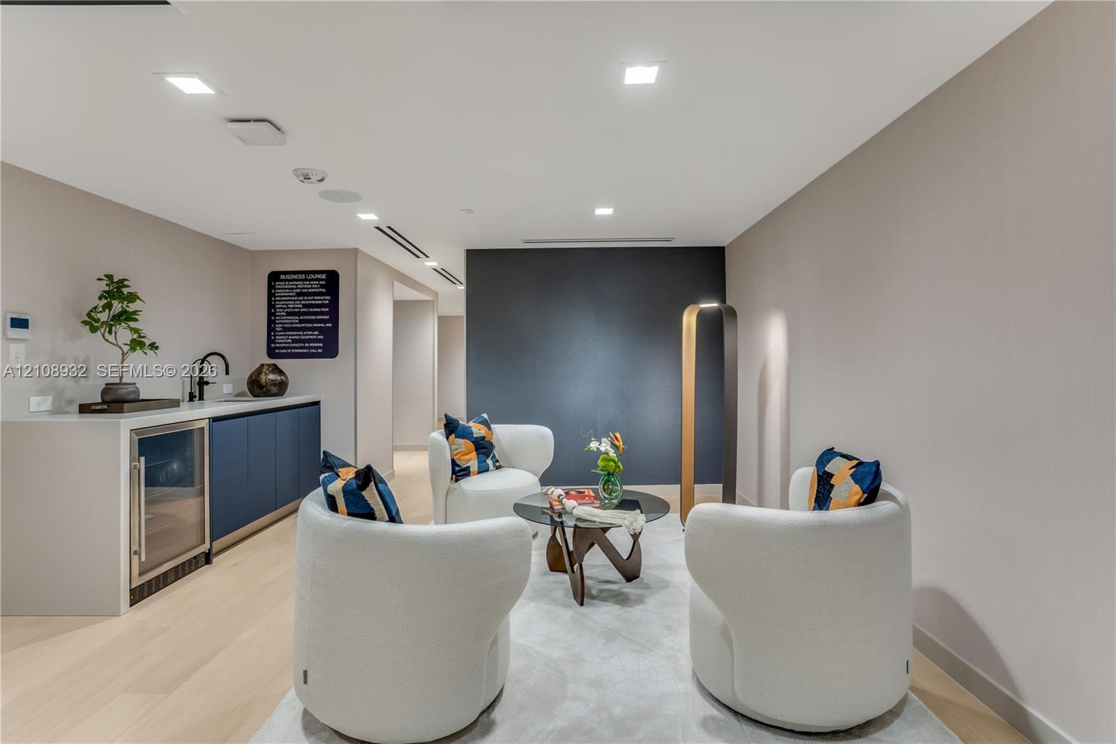 Wet bar featuring navy cabinetry, solid surface countertop, built-in beverage refrigerator, and matte black faucet, accented by recessed lighting and light wood-finish flooring