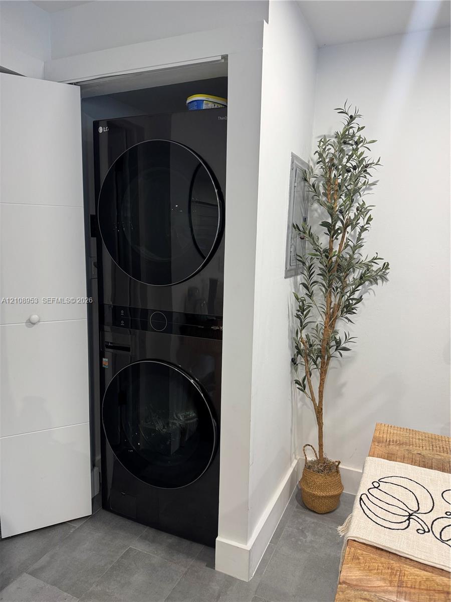 Built-in black stackable washer and dryer unit with a high-gloss finish, recessed within a dedicated enclosure