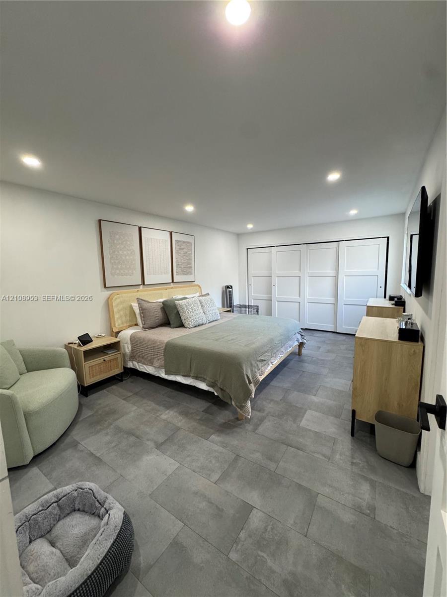 Large-format gray tile flooring, recessed ceiling lighting, and sliding multi-panel closet doors